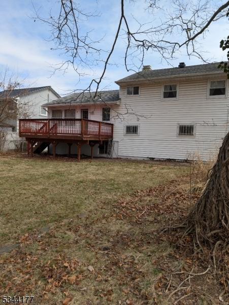 back of property featuring a wooden deck and a yard