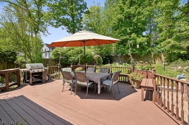 wooden deck with outdoor dining area, a fenced backyard, and area for grilling