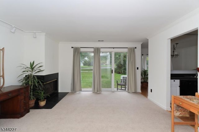 carpeted living room with ornamental molding, baseboards, visible vents, track lighting, and a multi sided fireplace