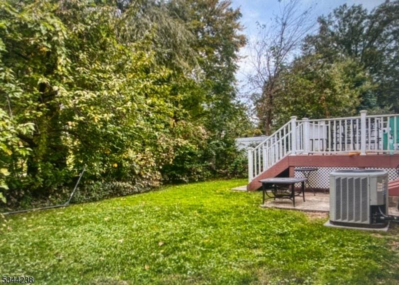 view of yard featuring stairway, central AC, and a wooden deck