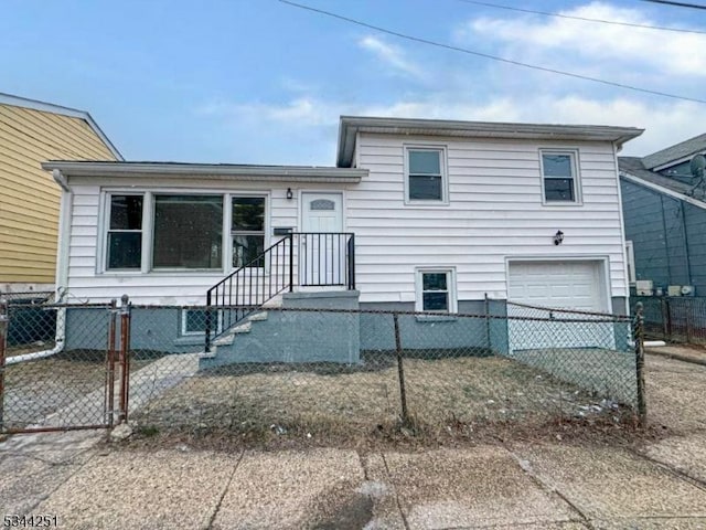 tri-level home with a fenced front yard, driveway, and a garage