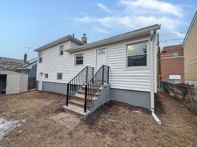 back of house with an outbuilding, a storage unit, fence, and a chimney