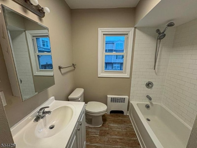 bathroom with toilet, wood finished floors, radiator, vanity, and shower / bathtub combination