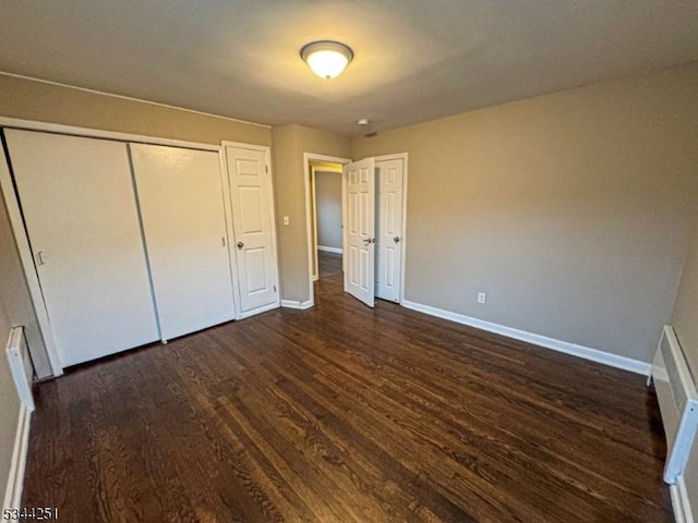 unfurnished bedroom featuring baseboards and dark wood-style flooring