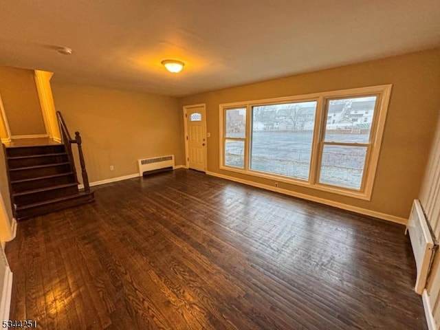 unfurnished living room featuring stairs, baseboards, dark wood-type flooring, and radiator heating unit