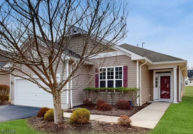 view of front of home featuring aphalt driveway, an attached garage, a shingled roof, and a front lawn