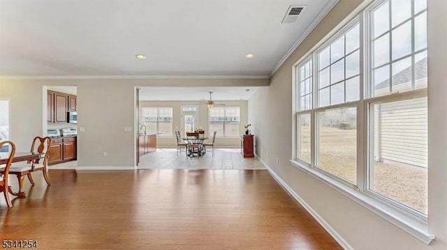 dining area featuring a ceiling fan, visible vents, baseboards, light wood-style floors, and crown molding