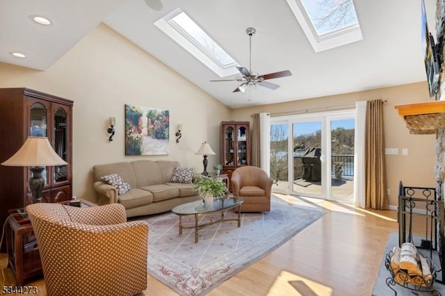 living area with a skylight, recessed lighting, ceiling fan, high vaulted ceiling, and wood finished floors