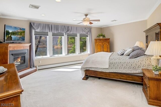 bedroom with baseboard heating, visible vents, ornamental molding, and carpet floors