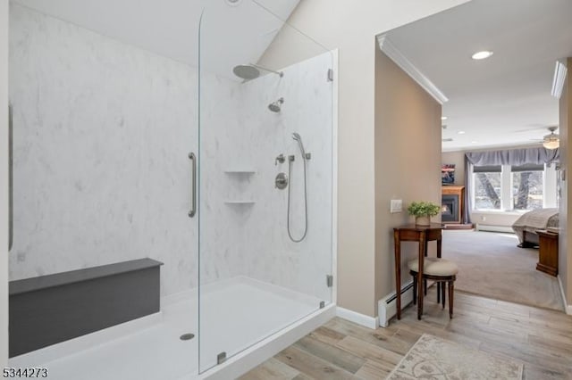 bathroom with walk in shower, connected bathroom, a baseboard heating unit, and wood finished floors