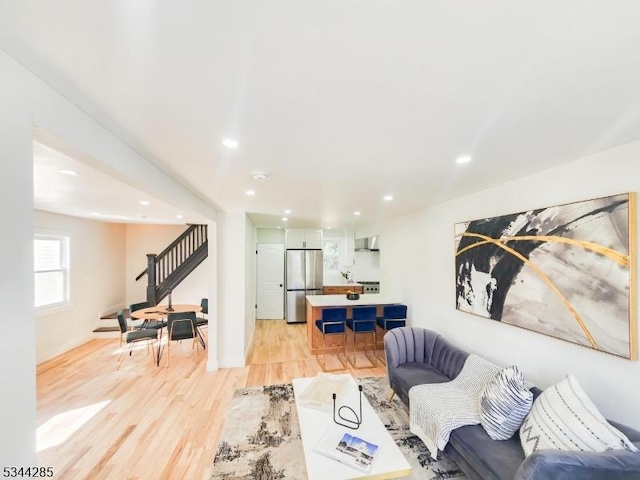 living area with recessed lighting, light wood-type flooring, and stairs