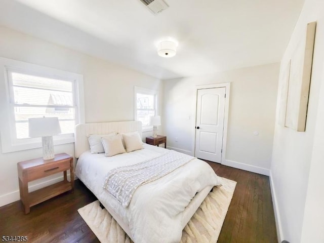 bedroom featuring visible vents, baseboards, and dark wood finished floors