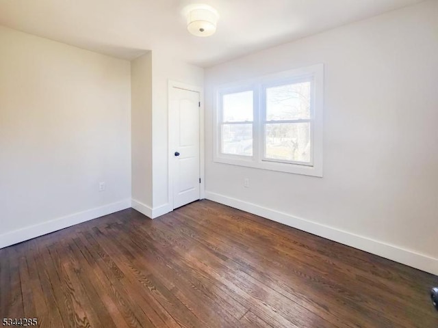 empty room featuring dark wood finished floors and baseboards