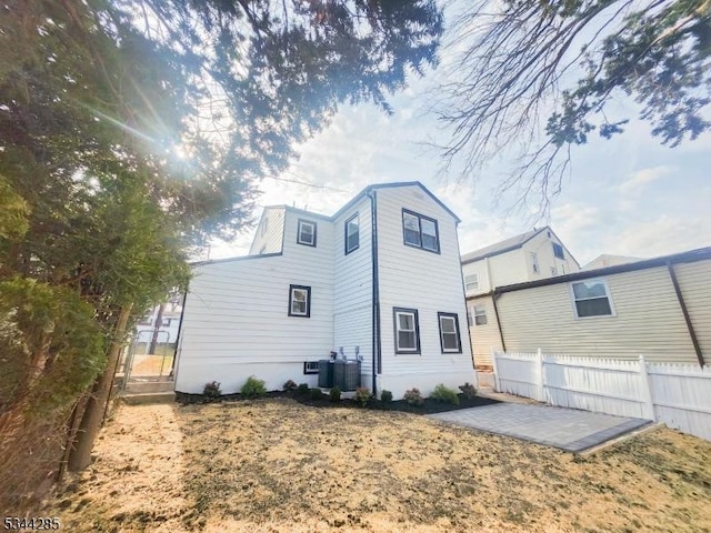 rear view of house featuring central AC unit, a patio, and fence