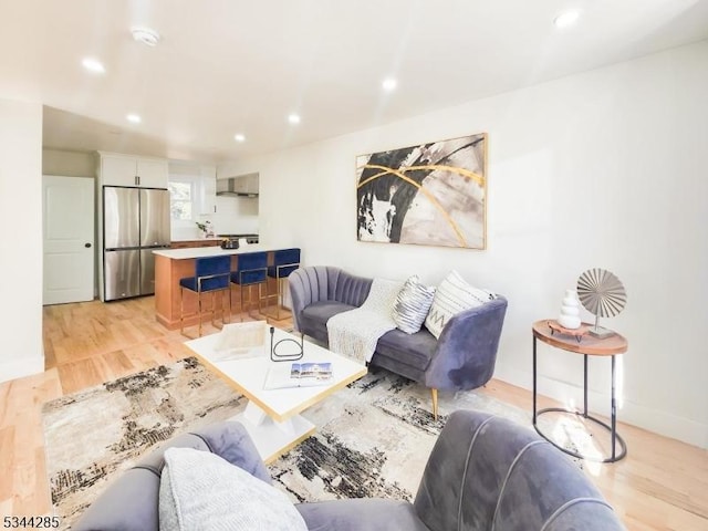 living area with recessed lighting, baseboards, and light wood-style flooring