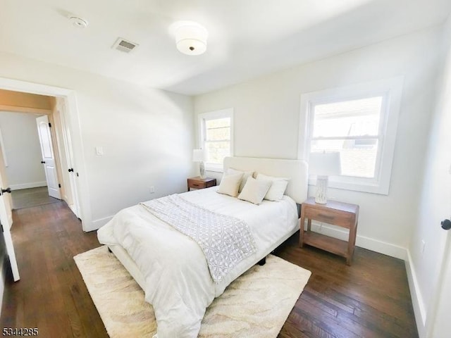 bedroom with visible vents, baseboards, and dark wood finished floors