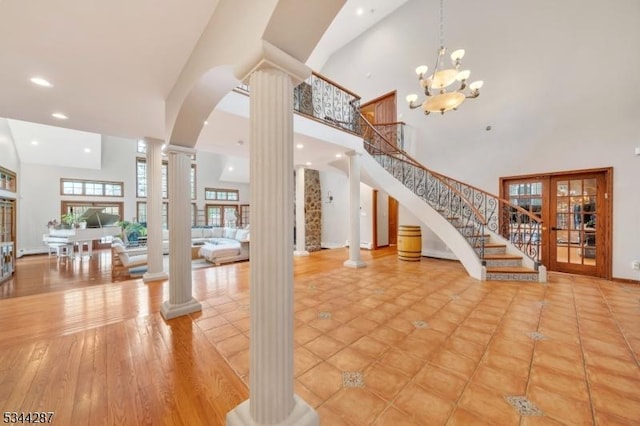 foyer entrance with stairs, decorative columns, arched walkways, and a towering ceiling