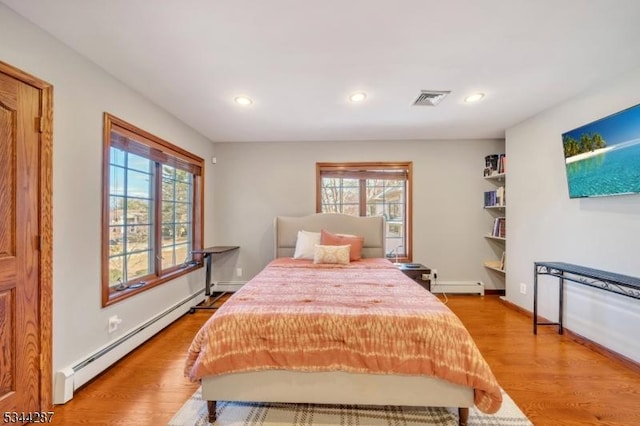 bedroom featuring visible vents, baseboard heating, and light wood-style floors