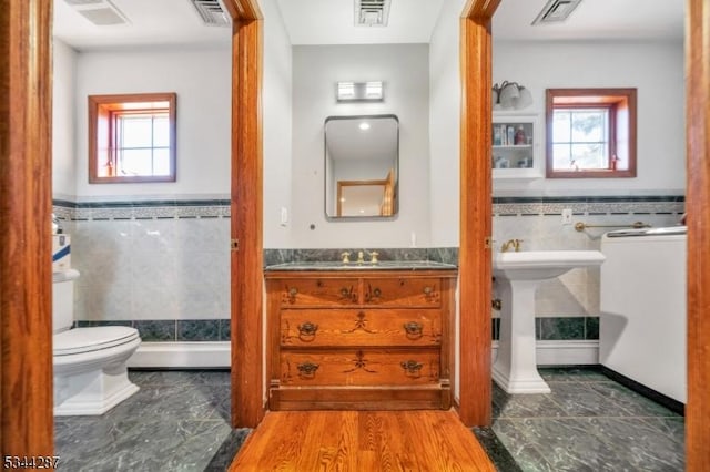 bathroom featuring tile walls, toilet, visible vents, and plenty of natural light