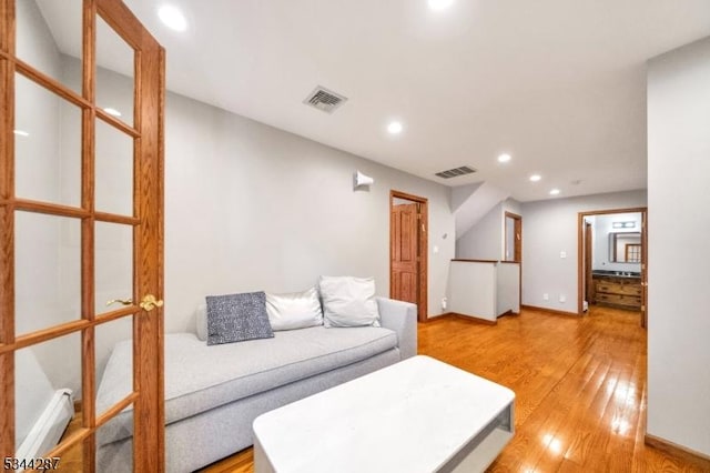 living area with light wood finished floors, visible vents, recessed lighting, and a baseboard radiator