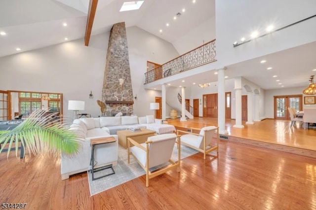 living room featuring wood finished floors, ornate columns, high vaulted ceiling, recessed lighting, and stairs