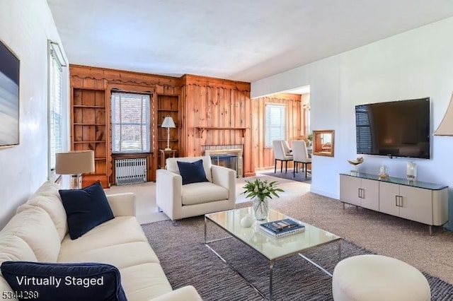 living room with a glass covered fireplace, radiator heating unit, and wooden walls