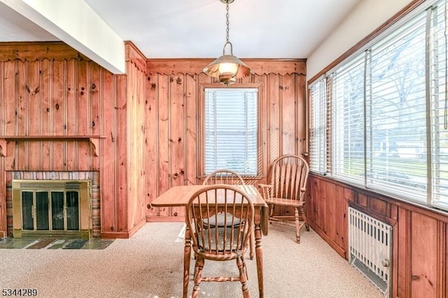 living area featuring radiator heating unit, wooden walls, a brick fireplace, and carpet floors
