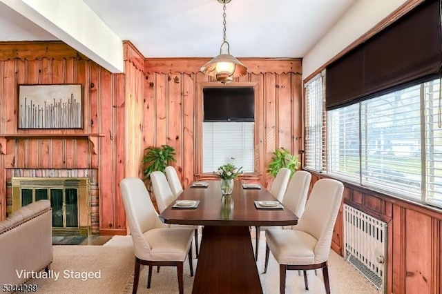 dining space featuring wooden walls and a fireplace