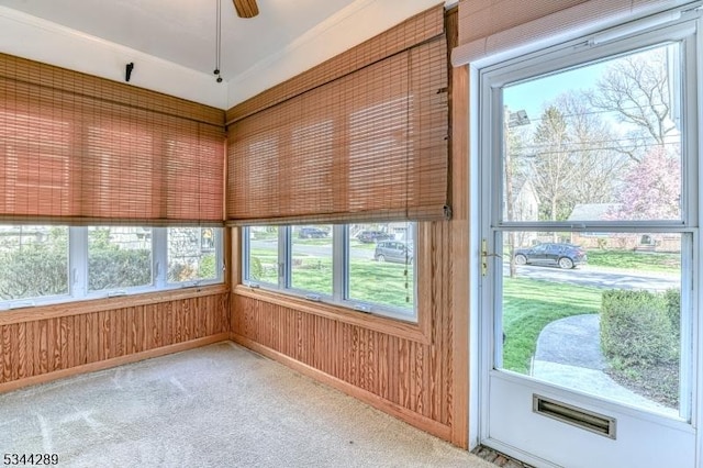 unfurnished sunroom with wooden walls, visible vents, and carpet flooring