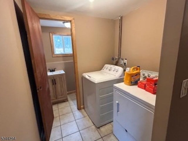 laundry room featuring washing machine and clothes dryer, laundry area, and light tile patterned floors