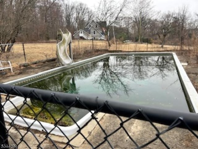 view of swimming pool featuring a fenced in pool, a water slide, and fence