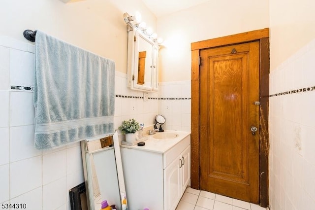 bathroom featuring tile patterned flooring, wainscoting, tile walls, and vanity