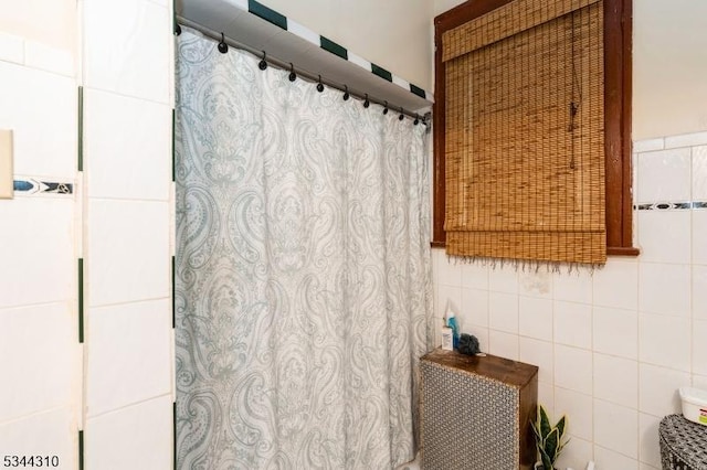 bathroom featuring a shower with curtain and tile walls