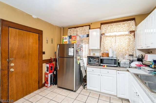 kitchen featuring backsplash, stainless steel appliances, white cabinets, light countertops, and light tile patterned floors