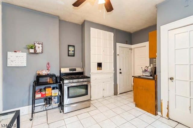 kitchen featuring light tile patterned flooring, dark countertops, ceiling fan, and stainless steel gas range