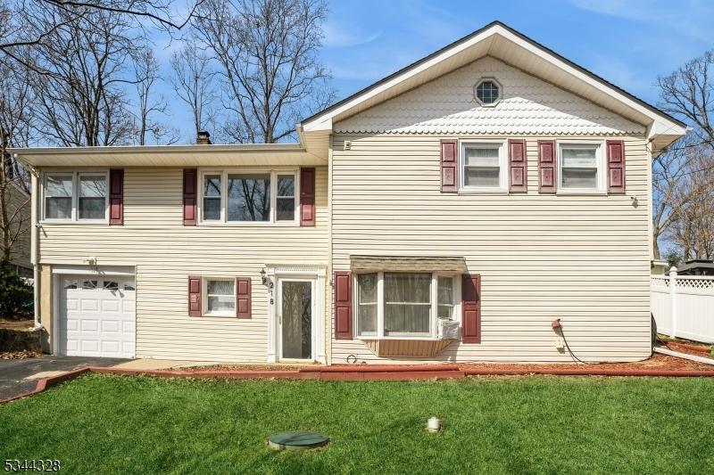 view of front facade with aphalt driveway, a garage, a front yard, and fence