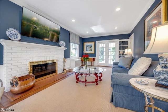 carpeted living area featuring a brick fireplace, recessed lighting, ornamental molding, and french doors