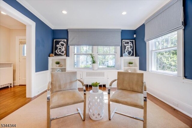 sitting room with ornamental molding, wood finished floors, and radiator
