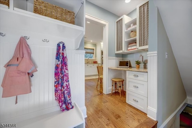mudroom featuring light wood-type flooring, recessed lighting, built in study area, and a wainscoted wall
