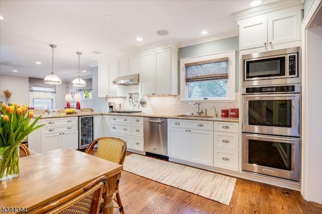 kitchen with wine cooler, white cabinetry, under cabinet range hood, a sink, and stainless steel appliances