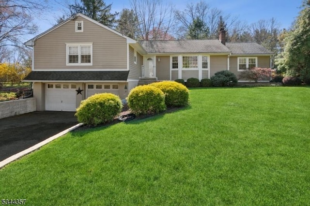 view of front of house featuring an attached garage, a chimney, driveway, and a front yard