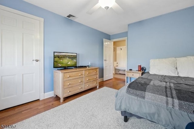 bedroom featuring visible vents, wood finished floors, baseboards, baseboard heating, and a ceiling fan