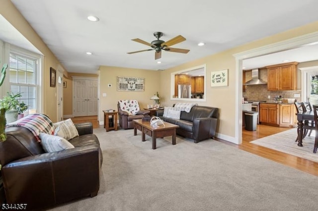 living area with light colored carpet, light wood-style floors, a ceiling fan, baseboards, and recessed lighting