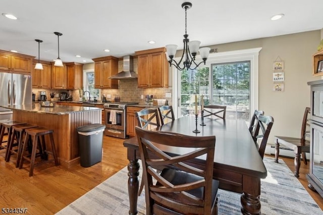 dining room featuring recessed lighting, an inviting chandelier, a wealth of natural light, and light wood-style flooring