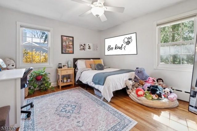 bedroom featuring ceiling fan, baseboards, a baseboard radiator, and wood finished floors
