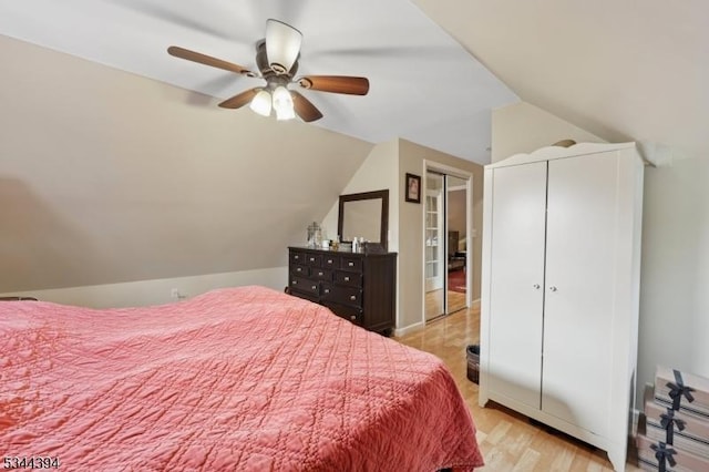 bedroom featuring light wood-style floors, lofted ceiling, and a ceiling fan