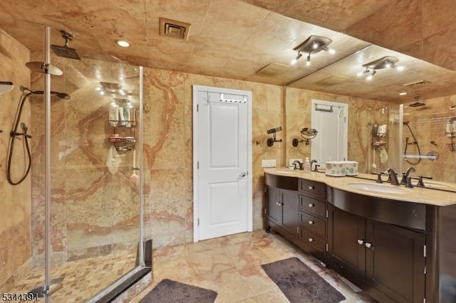 full bathroom with double vanity, a shower stall, visible vents, and a sink