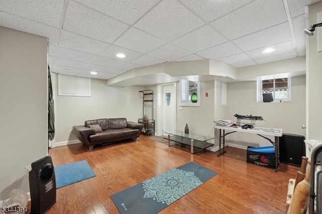 exercise room featuring baseboards, a paneled ceiling, wood finished floors, and recessed lighting