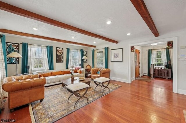 living area featuring beamed ceiling, wood finished floors, baseboards, and recessed lighting