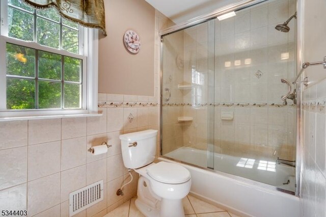 38 Beverly Dr, Hillsborough Twp, NJ 08844 - full bathroom featuring toilet, bath / shower combo with glass door, tile patterned floors, tile walls, and a wainscoted wall